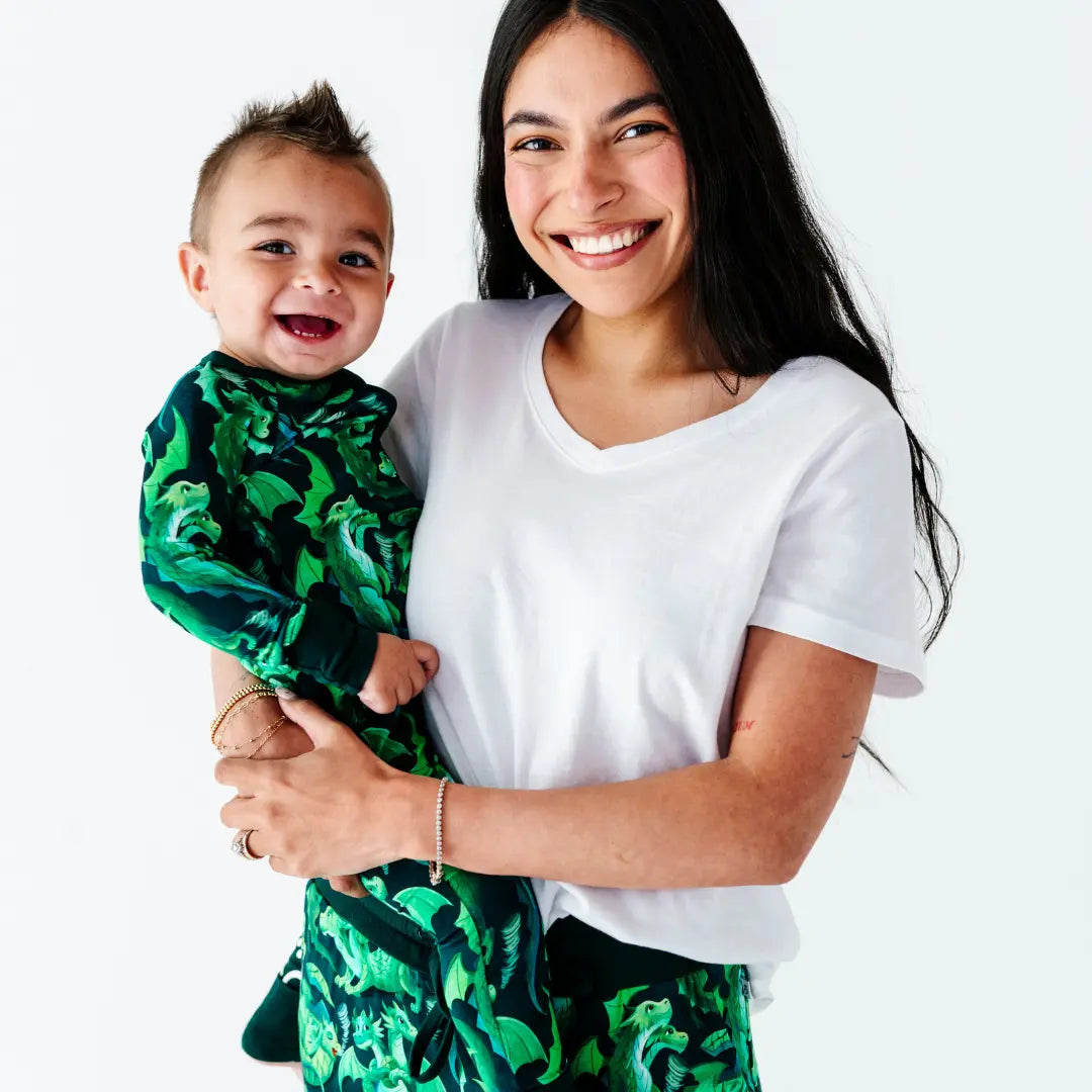 Woman holding a child wearing a green patterned outfit on a white background
