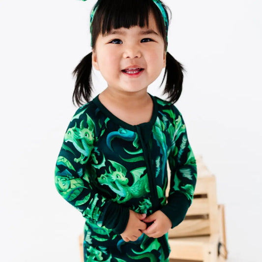 Child wearing a green dinosaur-patterned outfit on a white background