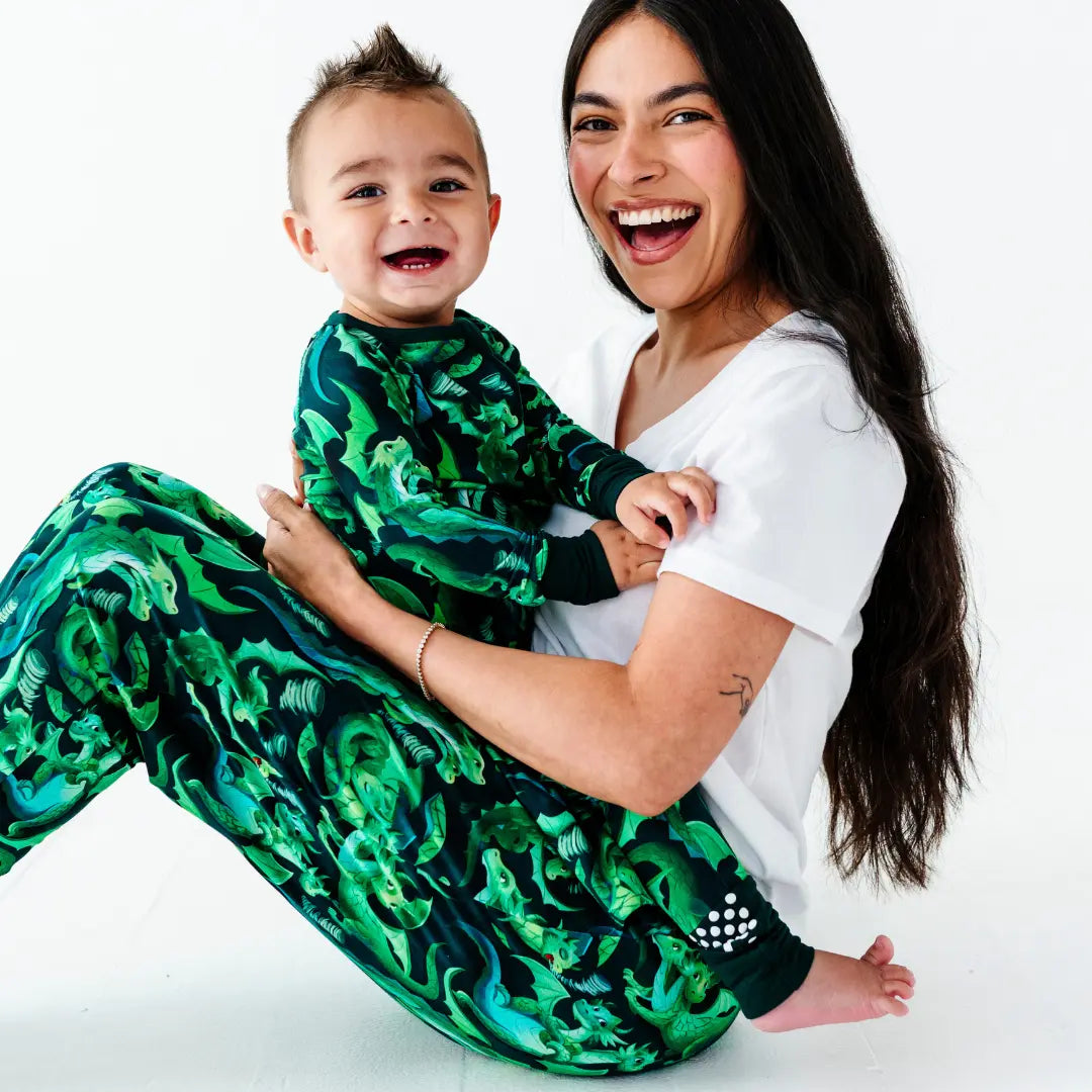 Woman holding a child wearing green patterned pajamas on a white background
