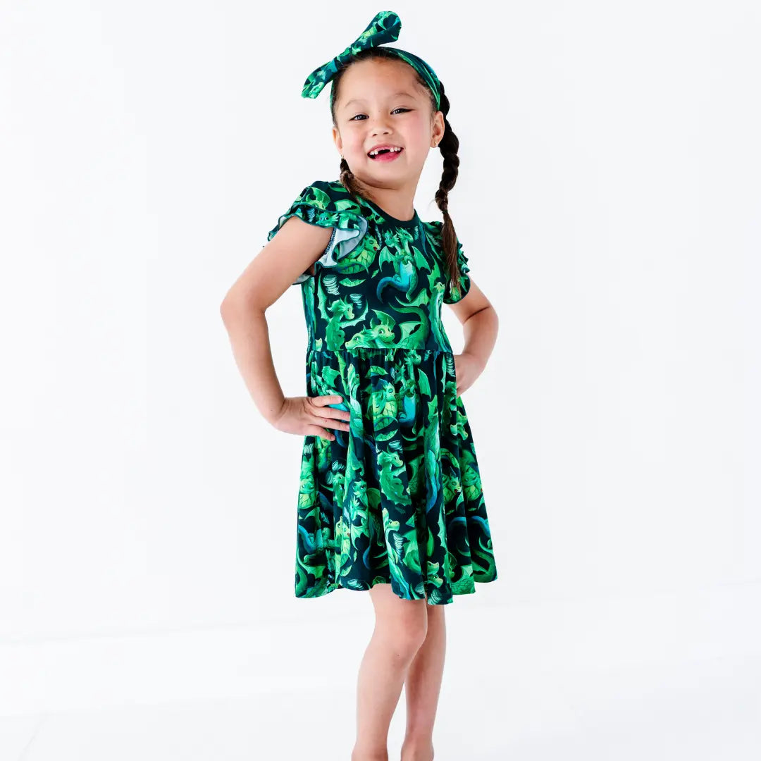 Young girl wearing a green camouflage dress with a matching headband on a white background