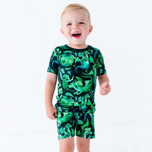 Child wearing a green dinosaur print outfit on a white background