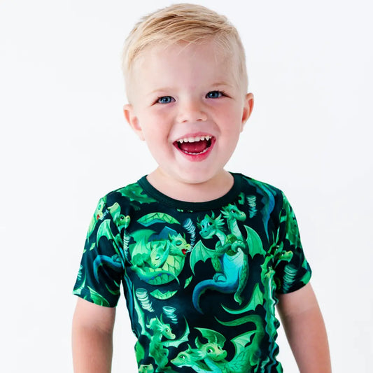 Child wearing a shirt with green dragon designs on a white background