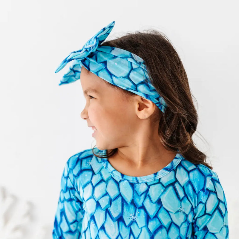 Child wearing a blue patterned headband and shirt on a white background