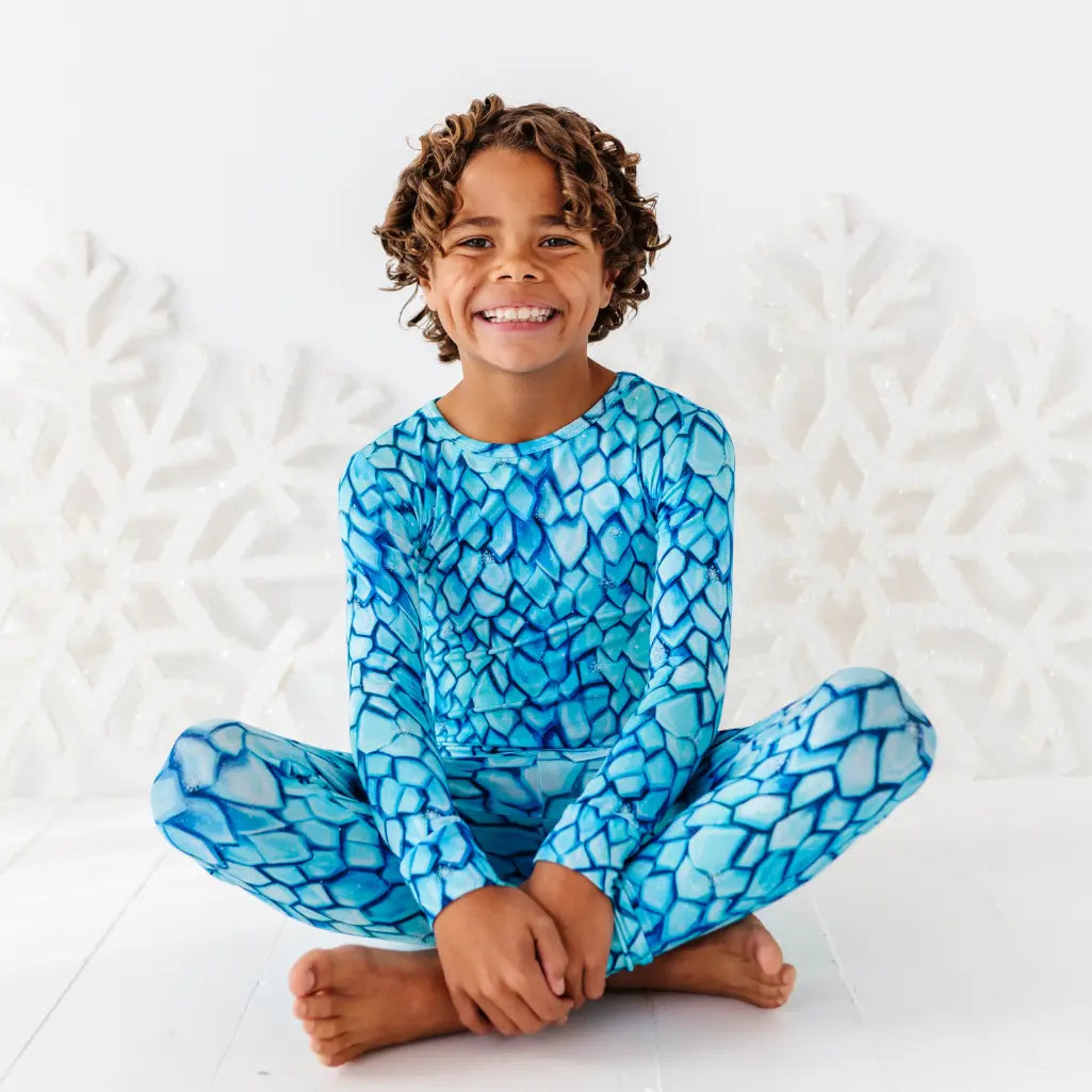 Child wearing a blue patterned outfit sitting on a white textured surface