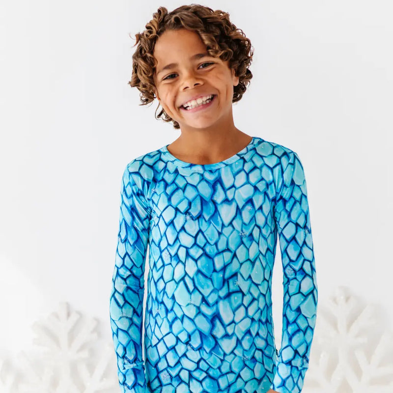 Child wearing a blue patterned long-sleeve shirt on a white background