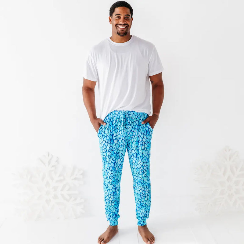 Man wearing a white t-shirt and blue patterned pants on a white background