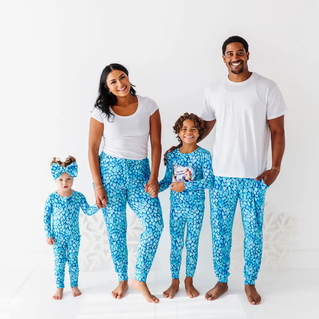 Family of four wearing matching blue and white pajamas on a white background