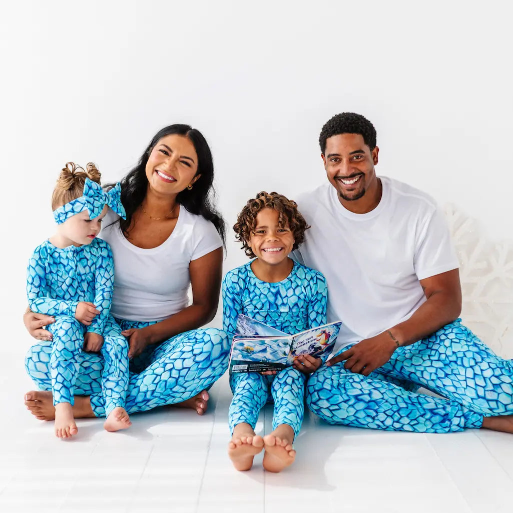 Family of four wearing matching blue and white pajamas on a white background
