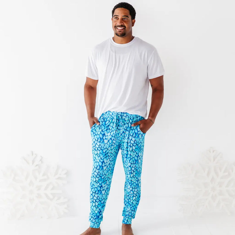 Man wearing a white t-shirt and blue patterned pants on a white background