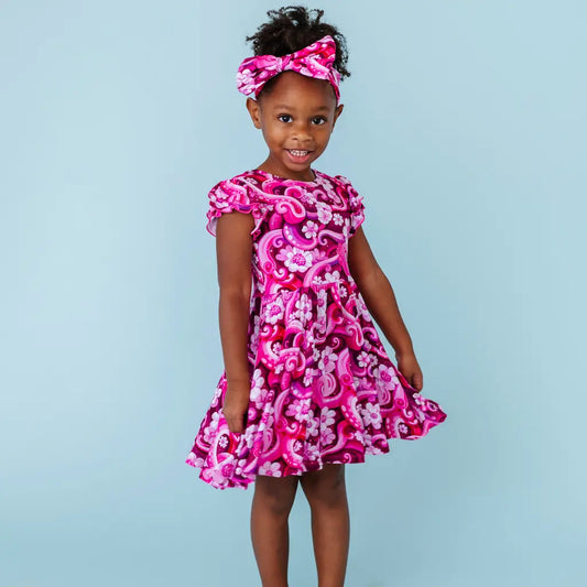 Young girl wearing a pink floral dress against a light blue background