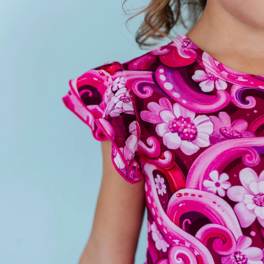 Young girl wearing a pink floral octopus-themed dress and headband against a light blue background