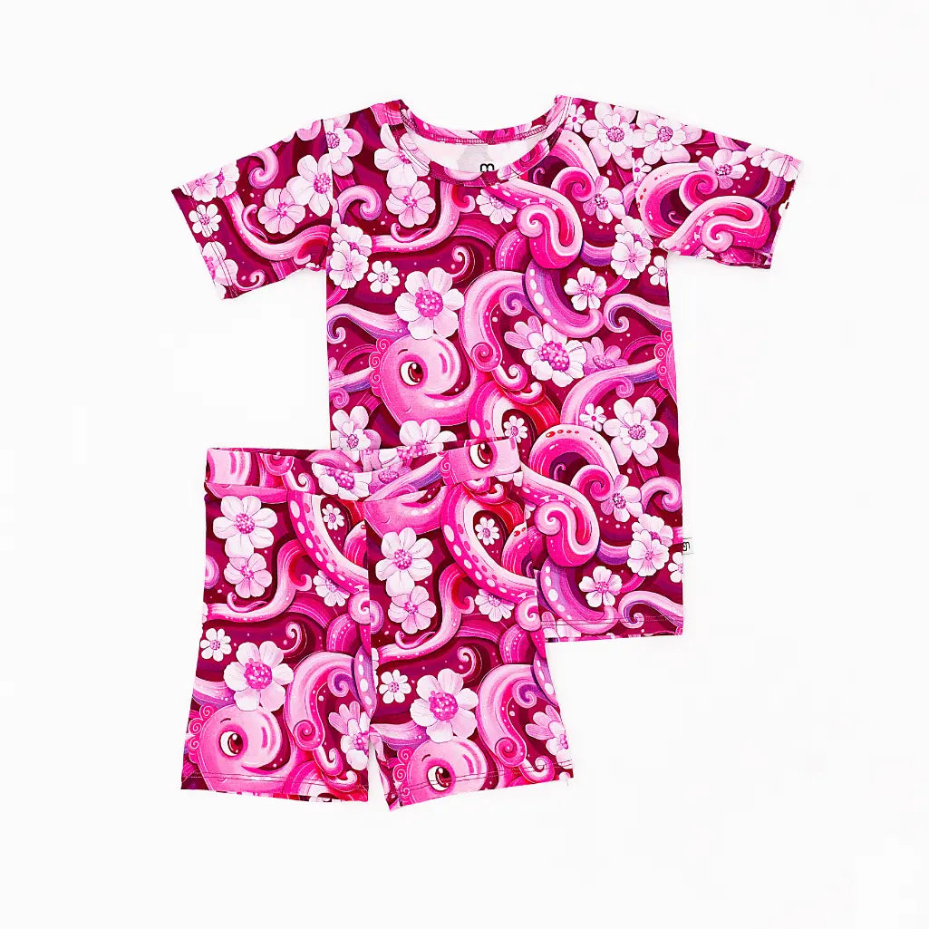 Pink and white floral and swirl patterned shirt and shorts set on a white background