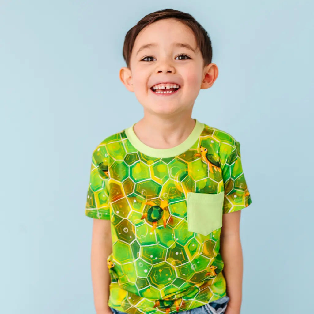 Child wearing a green and yellow patterned shirt against a light blue background