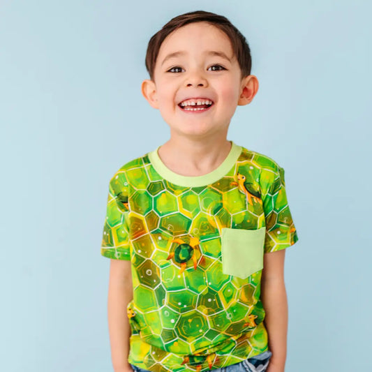 Child wearing a green and yellow patterned shirt against a light blue background