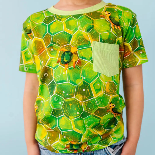 Green turtle pattern t-shirt worn by a person on a light blue background