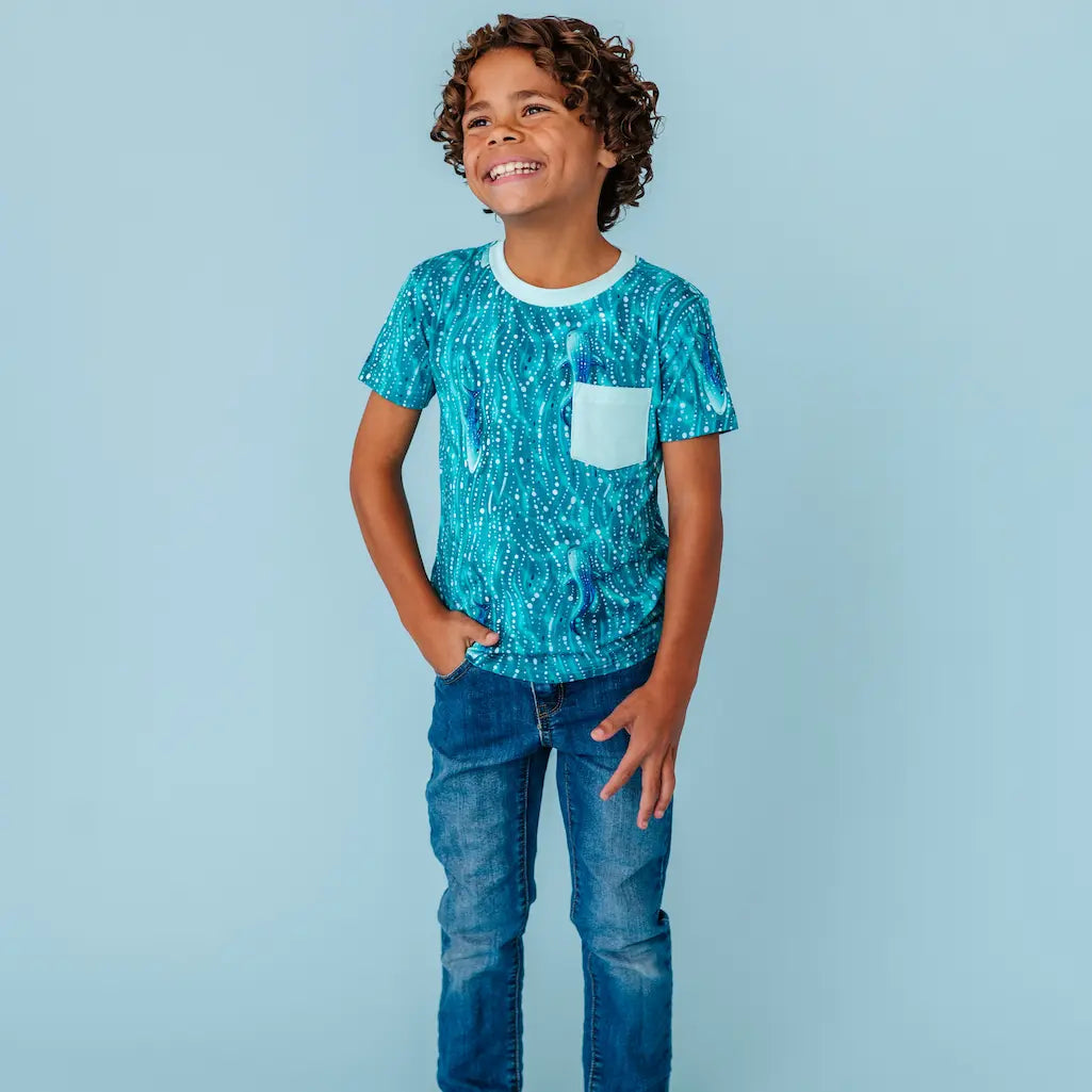 Child wearing a teal whale shark patterned t-shirt on a light blue background