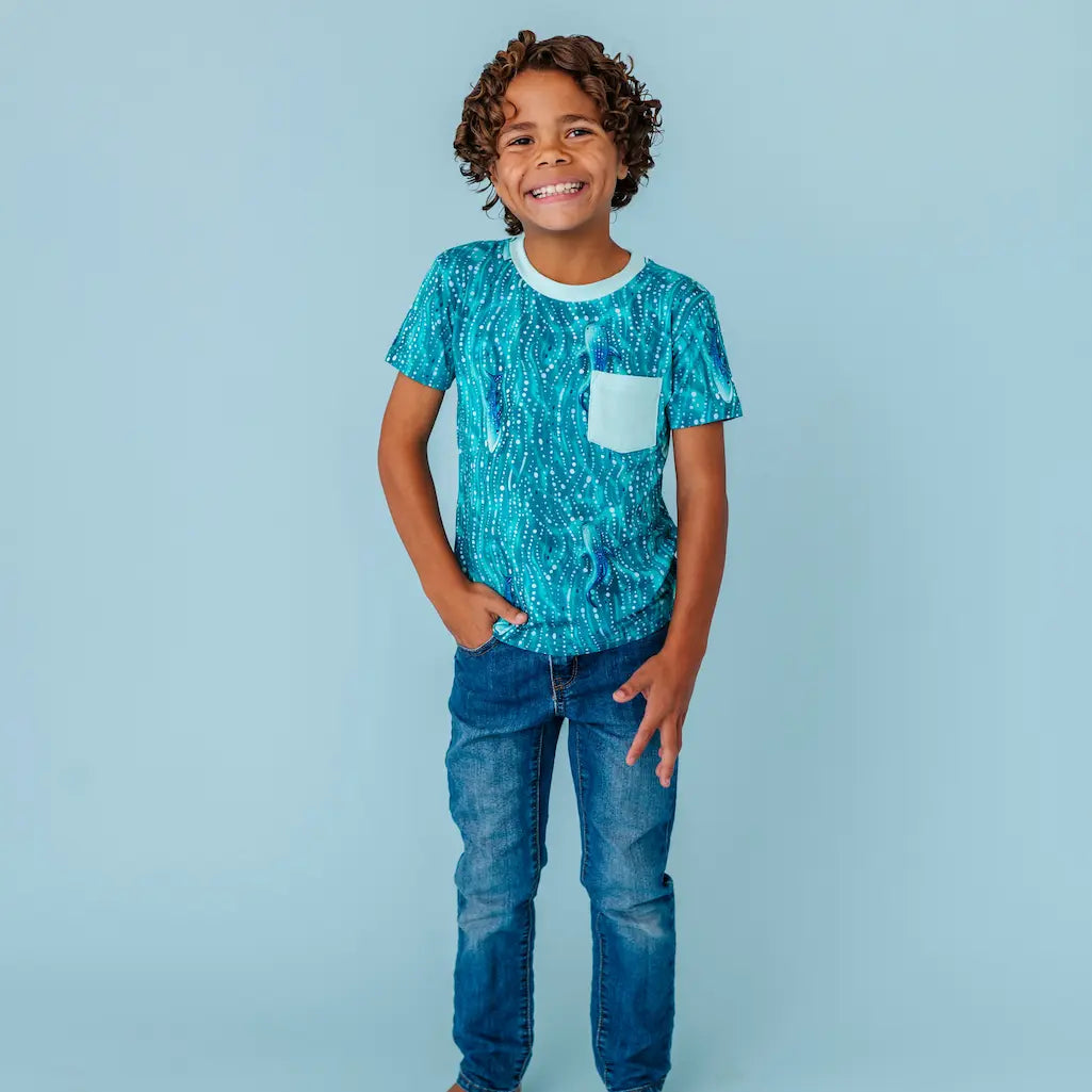 Child wearing a teal whale shark patterned t-shirt on a light blue background