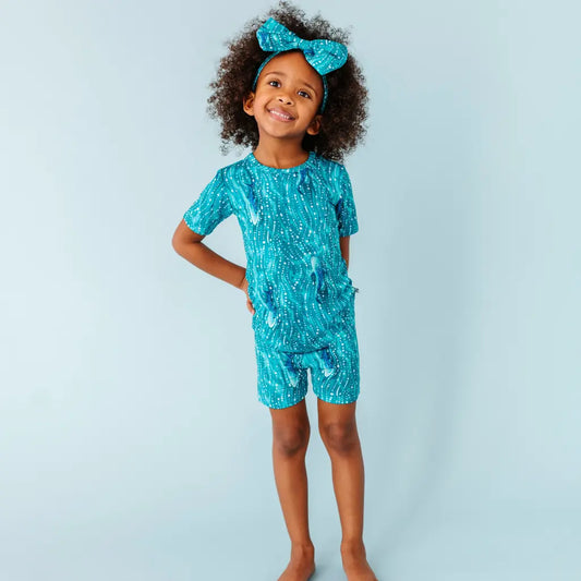 Child wearing a turquoise outfit with white patterns against a light blue background