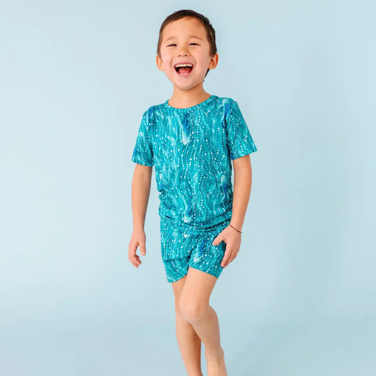 Child wearing a turquoise swim set with white patterns on a light blue background