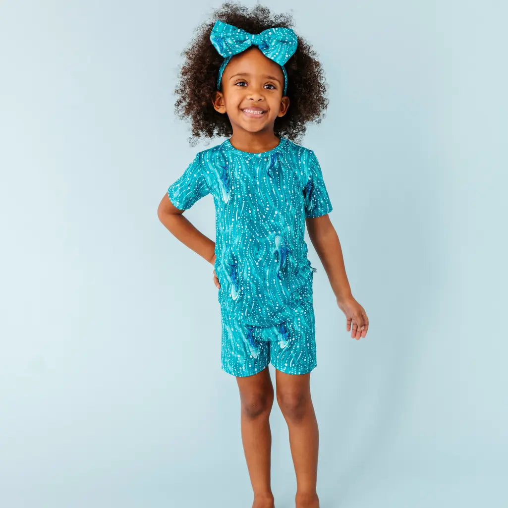 Child wearing a blue patterned outfit with a matching headband against a light blue background