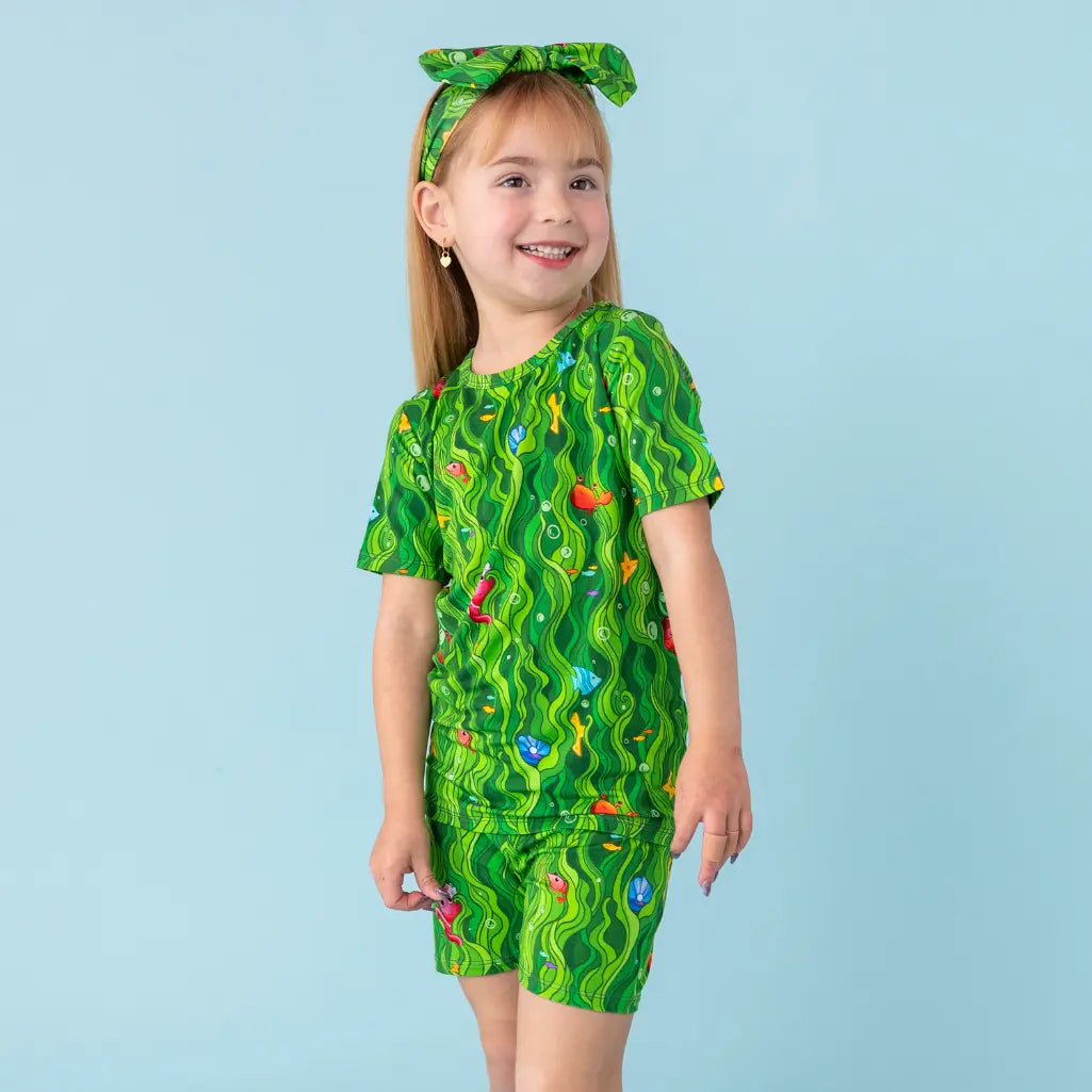 Child wearing a green patterned outfit on a light blue background