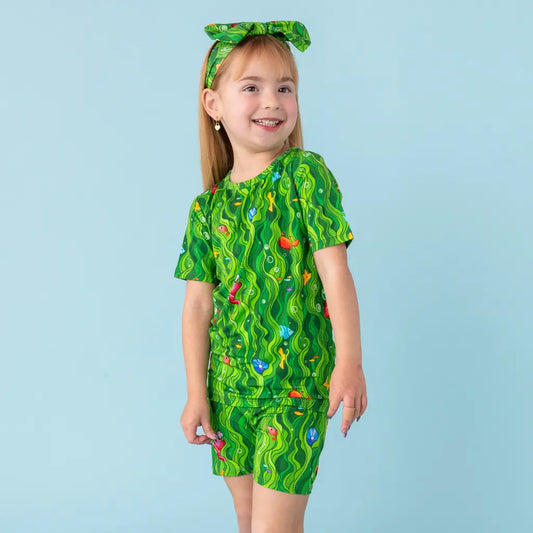 Child wearing a green patterned outfit on a light blue background