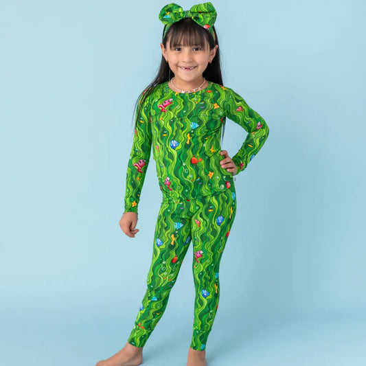 Child wearing a green patterned onesie against a light blue background