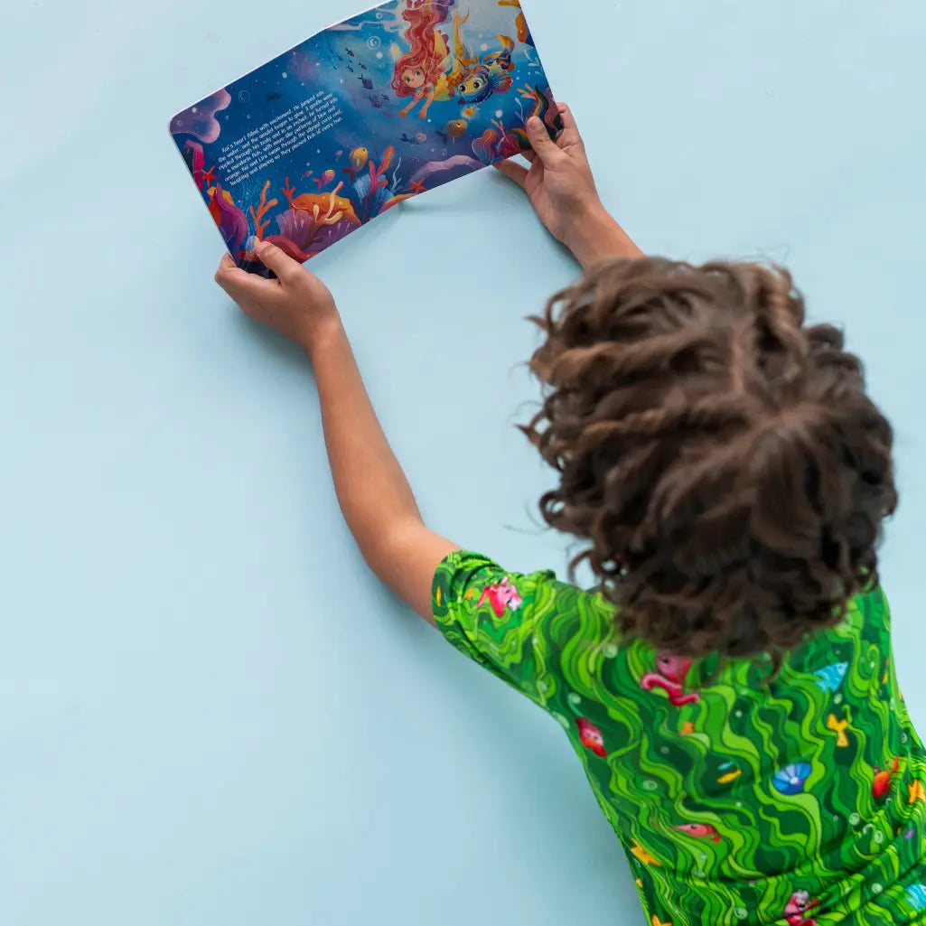 Child reading a colorful book against a light blue background