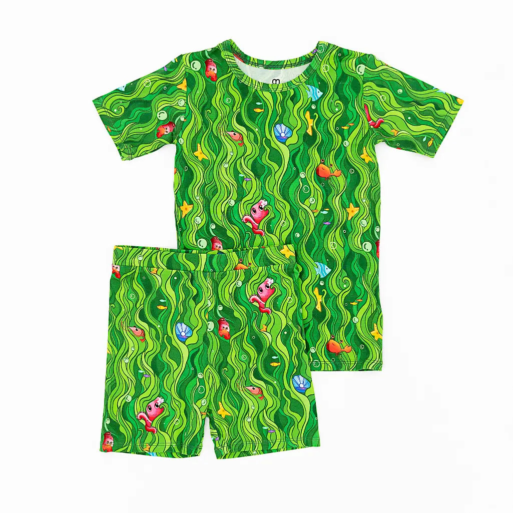 Children's swimsuit set with green wavy pattern and cartoon characters on a white background