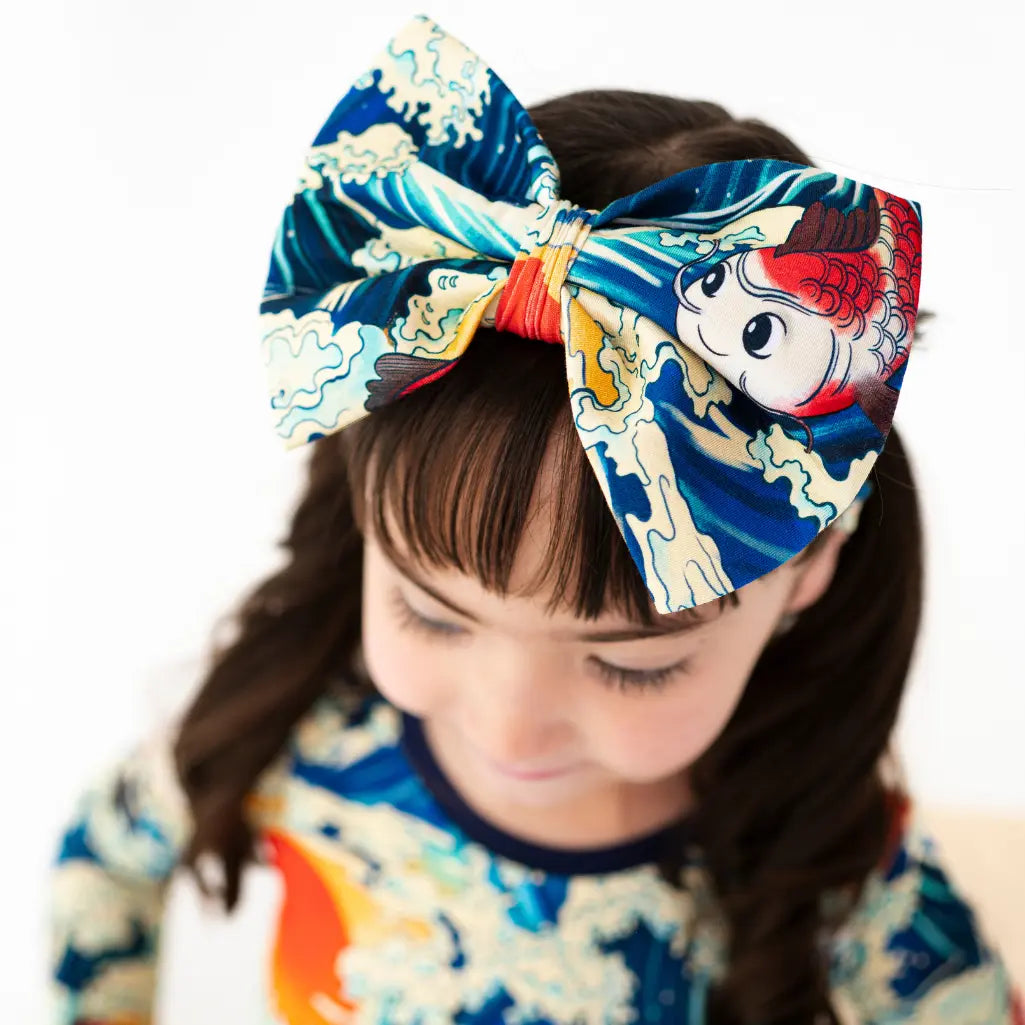 Child wearing a large, colorful headband with a design of a cartoon character on a white background