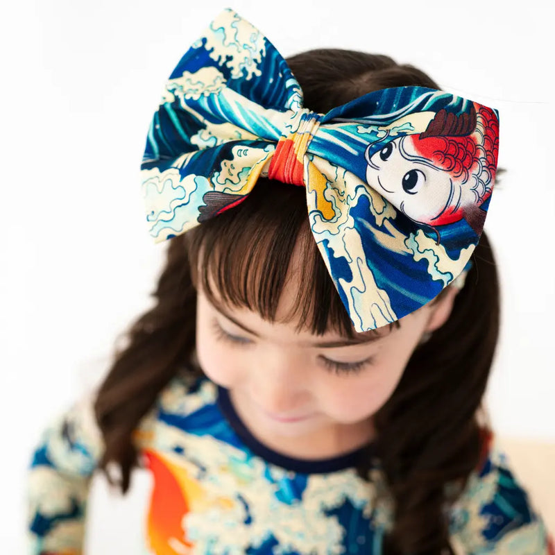 Child wearing a large, colorful headband with a design of a cartoon character on a white background