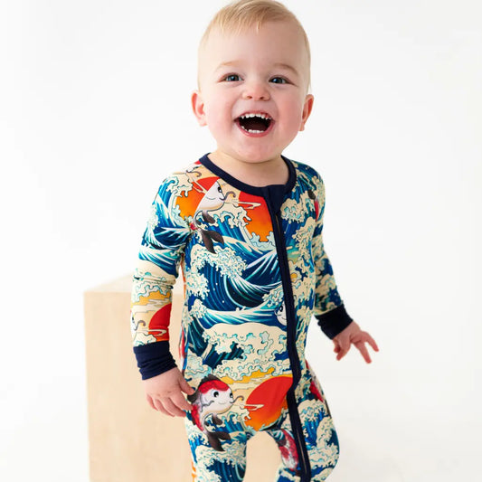 Baby wearing a colorful onesie with wave design on a white background