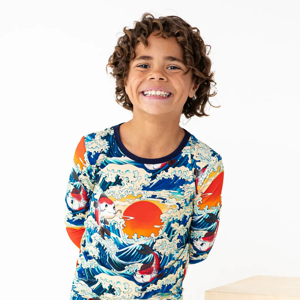 Child wearing a colorful long-sleeve shirt with wave design on a white background
