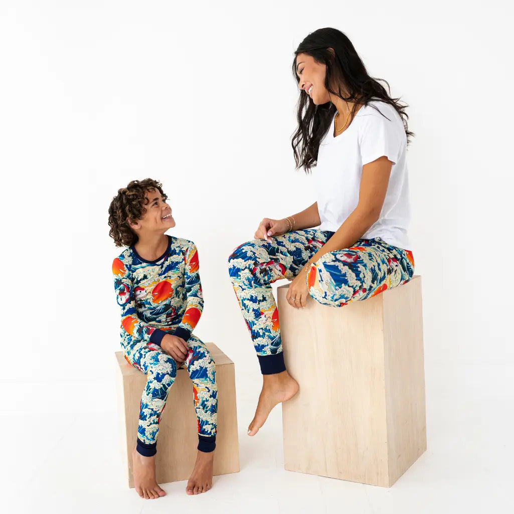 Two people wearing colorful pajamas sitting on wooden blocks against a white background