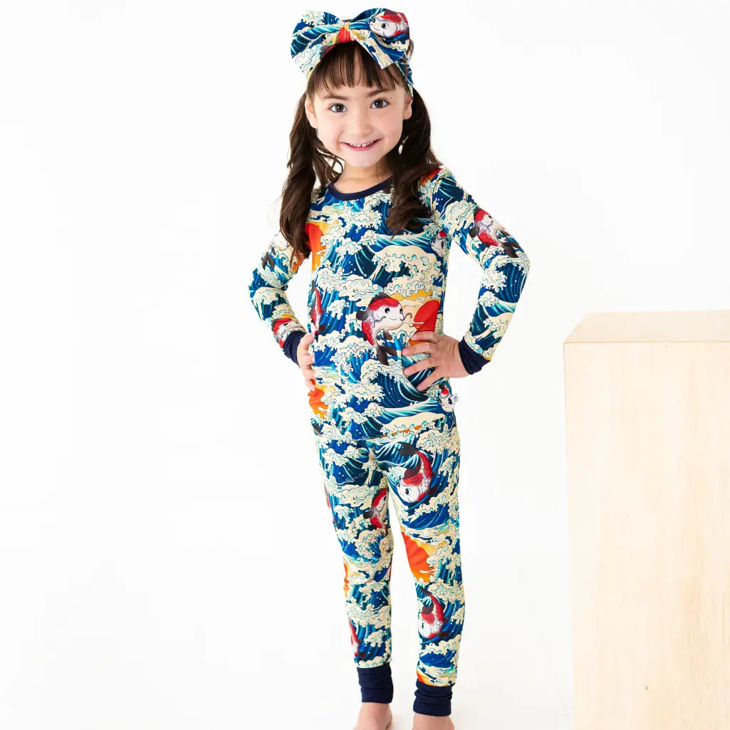 Child wearing a colorful onesie with a pattern of cartoon characters on a white background