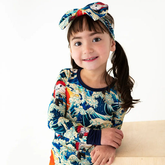 Child wearing a colorful outfit with a headband on a white background