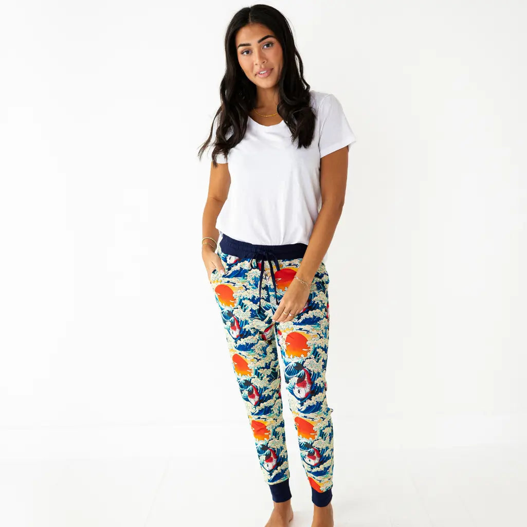 Woman wearing colorful floral jogger pants with a white top on a white background
