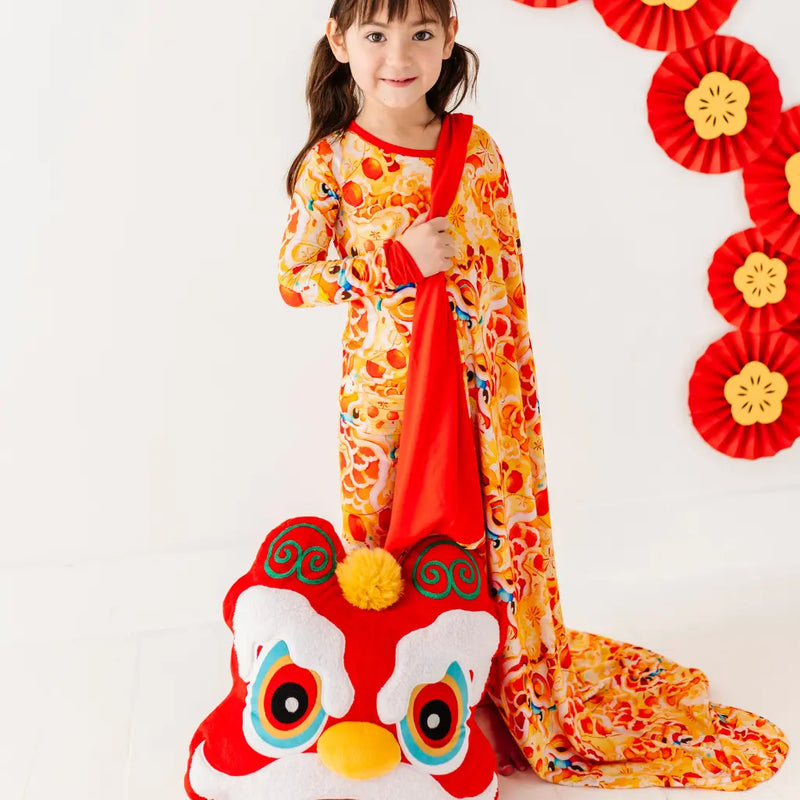 Child in a colorful traditional outfit with a red and white dragon costume on a white background