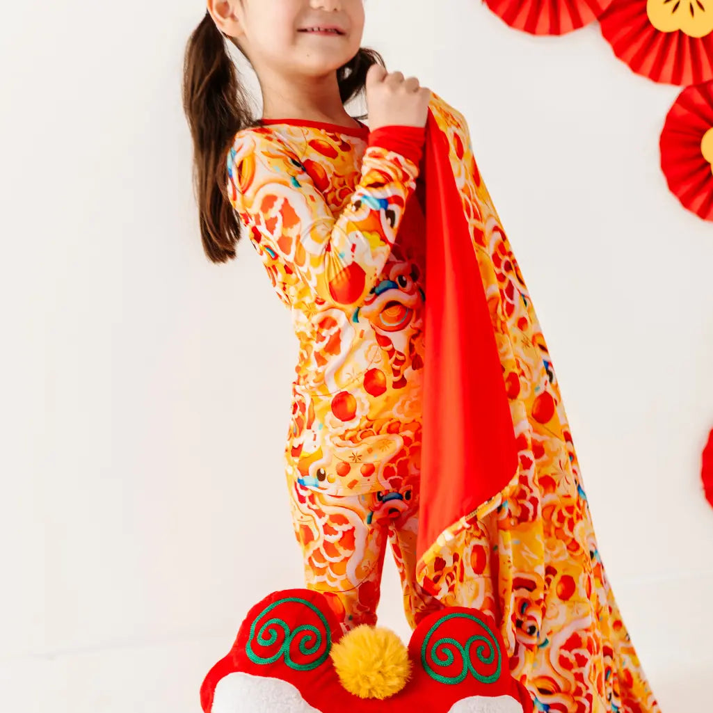 Child wearing a colorful outfit with a red scarf, standing against a white background.