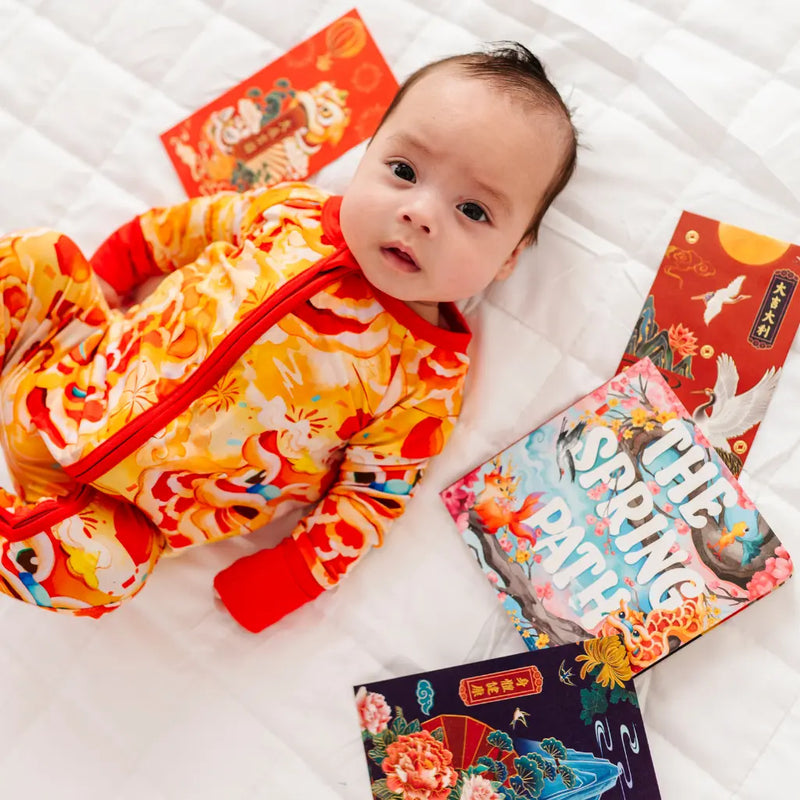 Baby in a colorful outfit with books on a white surface