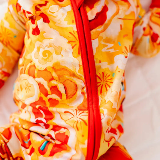 Close-up of a baby in a colorful floral outfit with a red zipper.