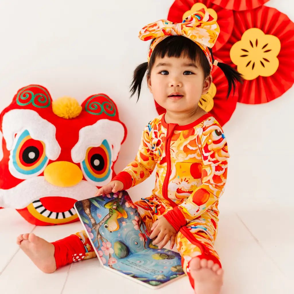 Child in a colorful outfit with a dragon costume and red decorations.