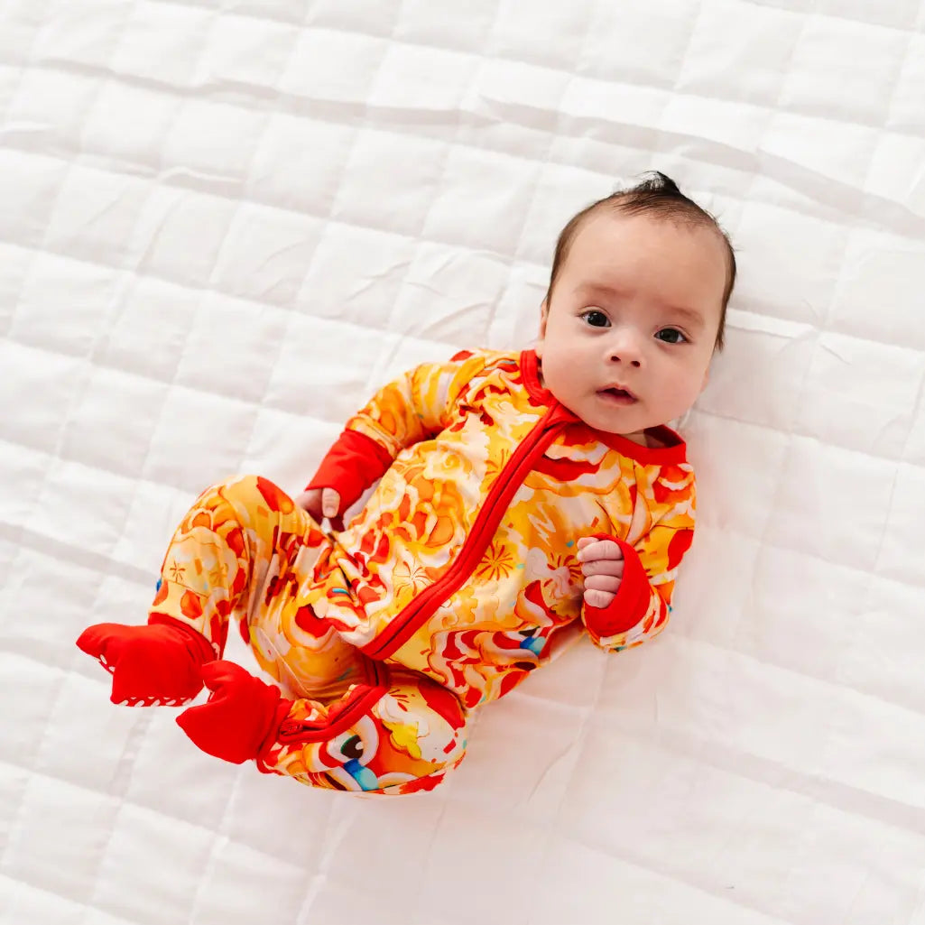 Baby wearing a colorful outfit with red and orange elements on a white blanket