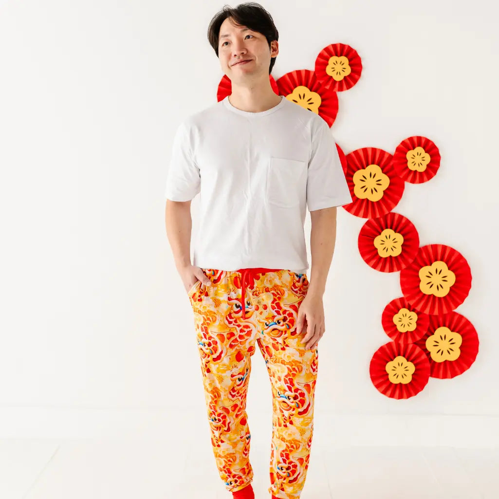 Person wearing a white shirt and colorful pants with decorative red and yellow elements on a white background