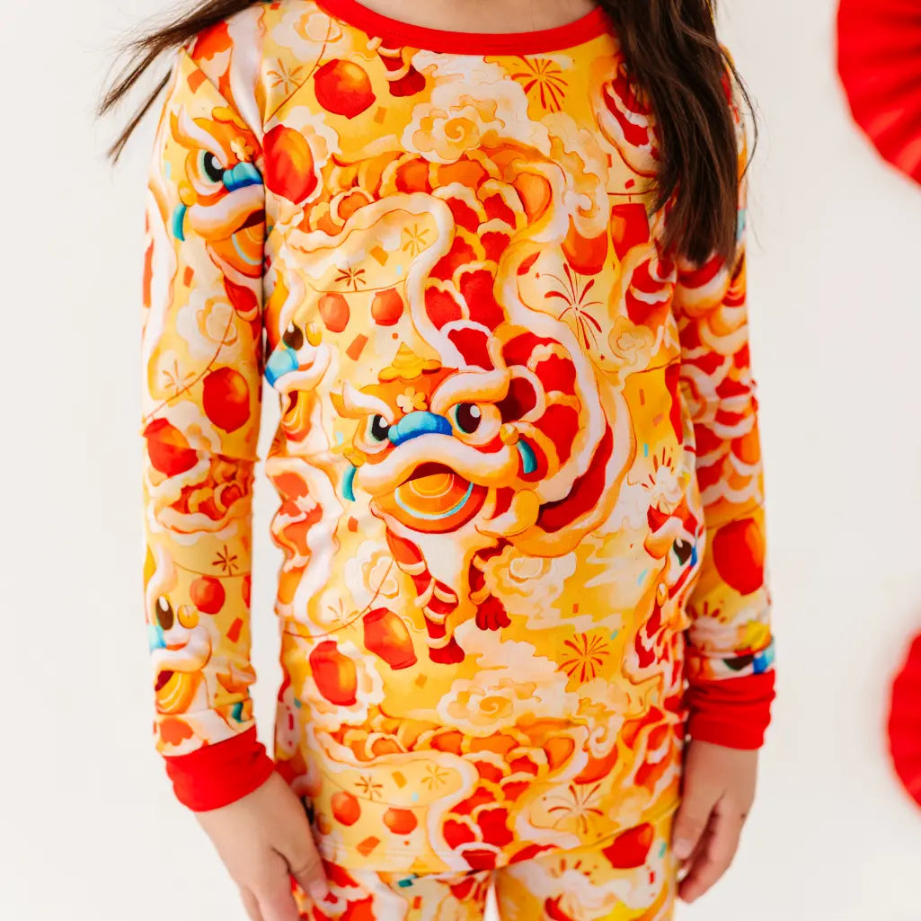 Child wearing a colorful dragon-themed onesie on a white background
