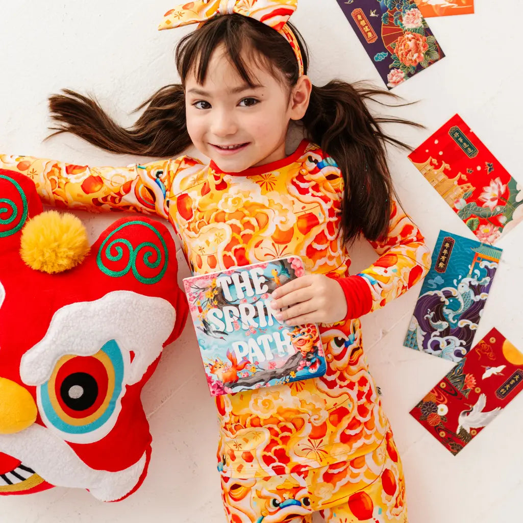 Child in a colorful outfit holding a book with festive decorations around