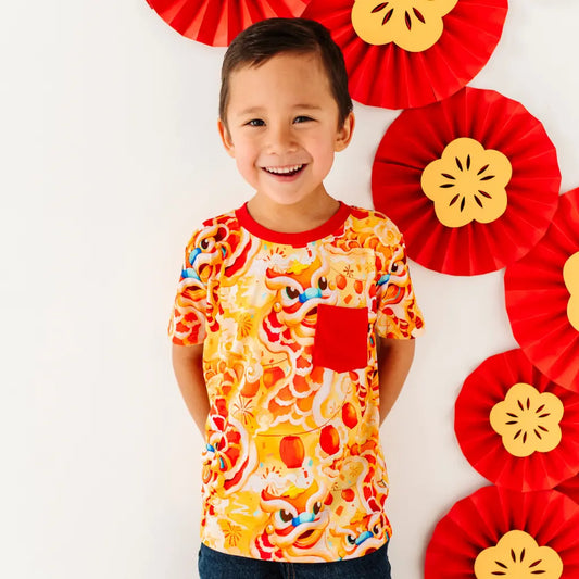 Child wearing a colorful shirt with decorative red and yellow fans in the background