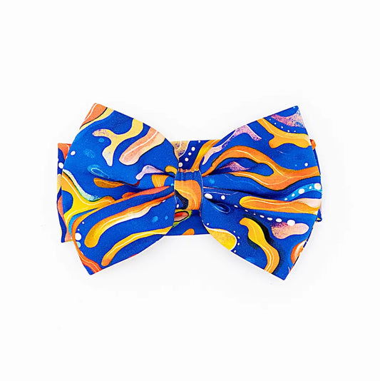 A bow headband with a vibrant pattern of swirling blue and orange with maze-like designs.