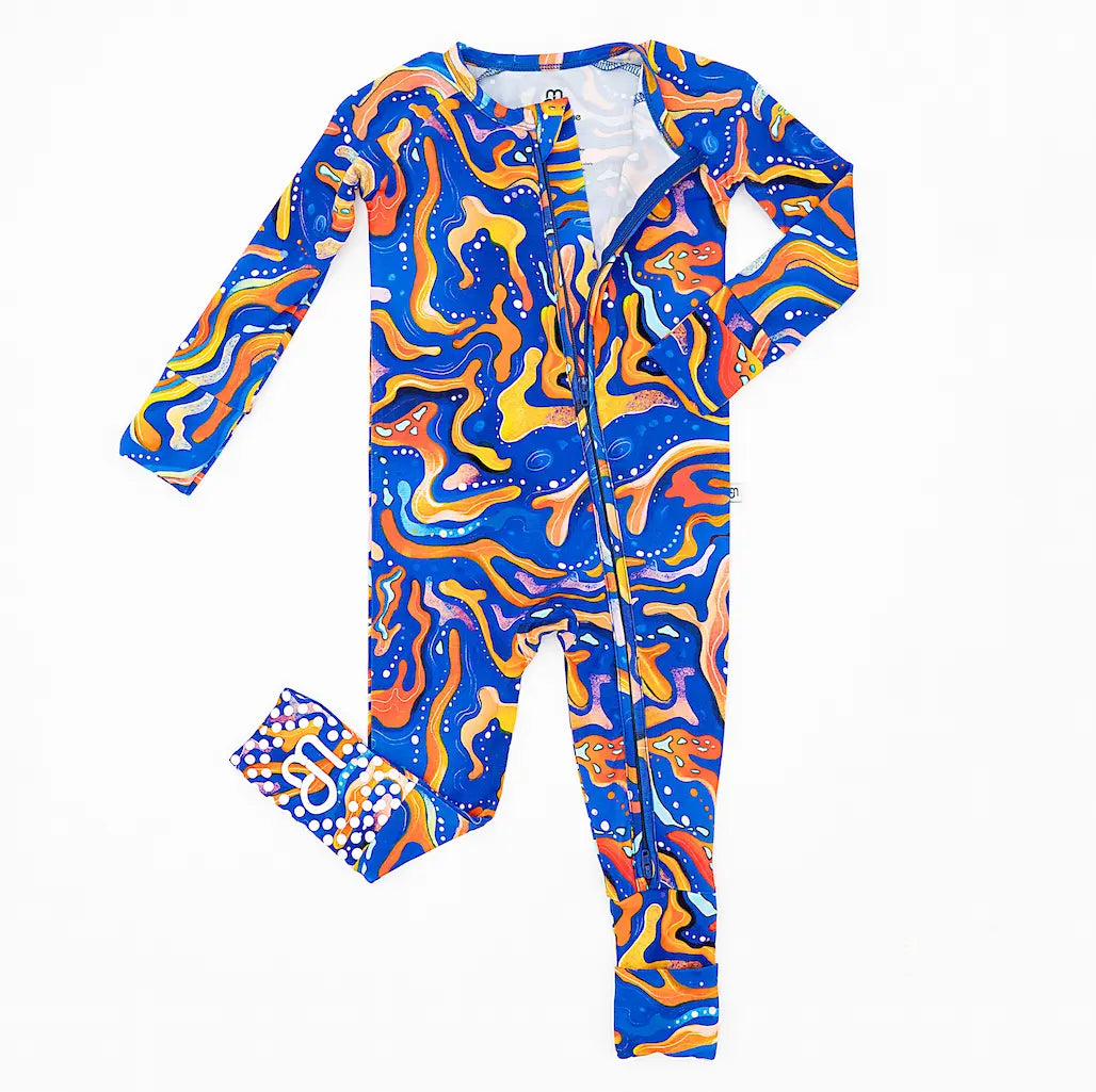 A vibrant, long-sleeved baby pajama onesie with a geometric blue and orange maze pattern, featuring fold-over mittens and convertible foot covers.