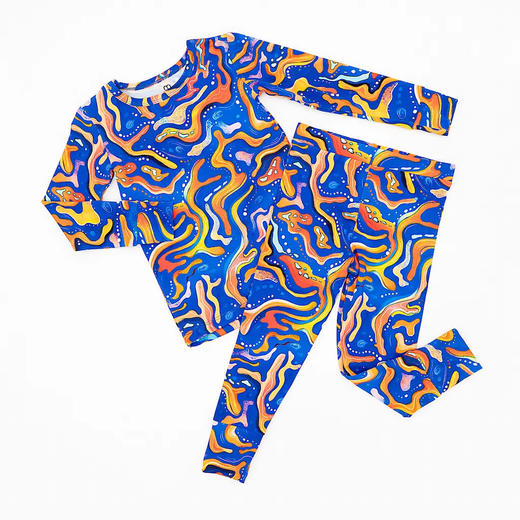 A set of children's pajamas with a vibrant pattern of swirling blue and orange with maze-like designs.